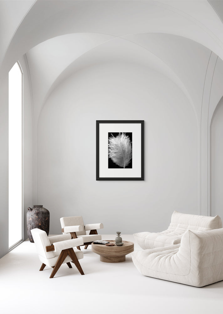 Protection white feather art print is displayed on a wall within a mostly white, modern minimalist living space.